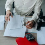 Profesional bisnis mengatur dokumen di meja kerja kantor sebagai ilustrasi pembuatan standar operasional prosedur perusahaan